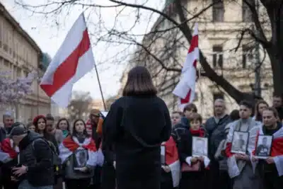 Belarusian diaspora protest in 2025, with people holding portraits of political prisoners and waving white-red-white flags, demonstrating support for democracy in exile.